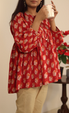 A woman wearing a red hand block printed cotton top with three-quarter sleeves and a round neckline.